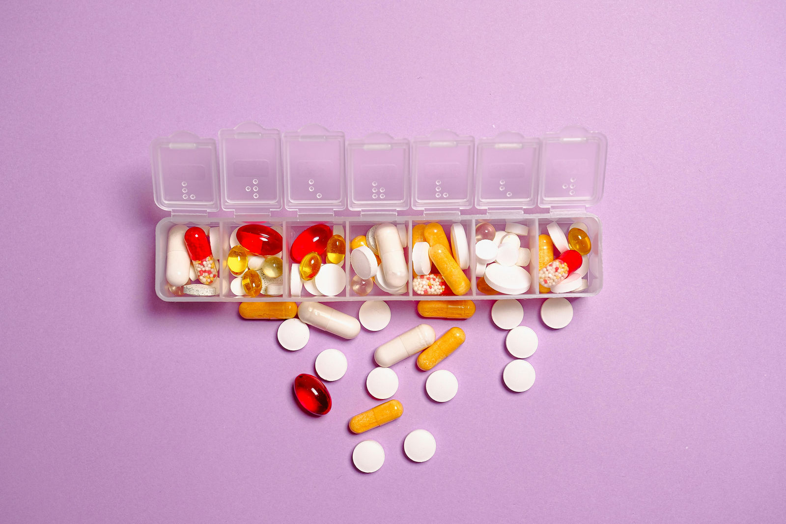 picture of weekly pill organizer opened up with pills coming out. 