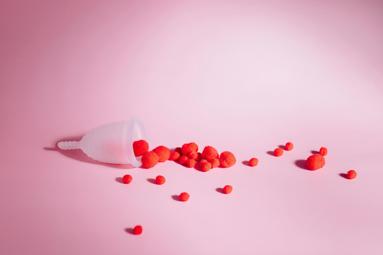 red cotton balls spilling out of a clean menstrual cup