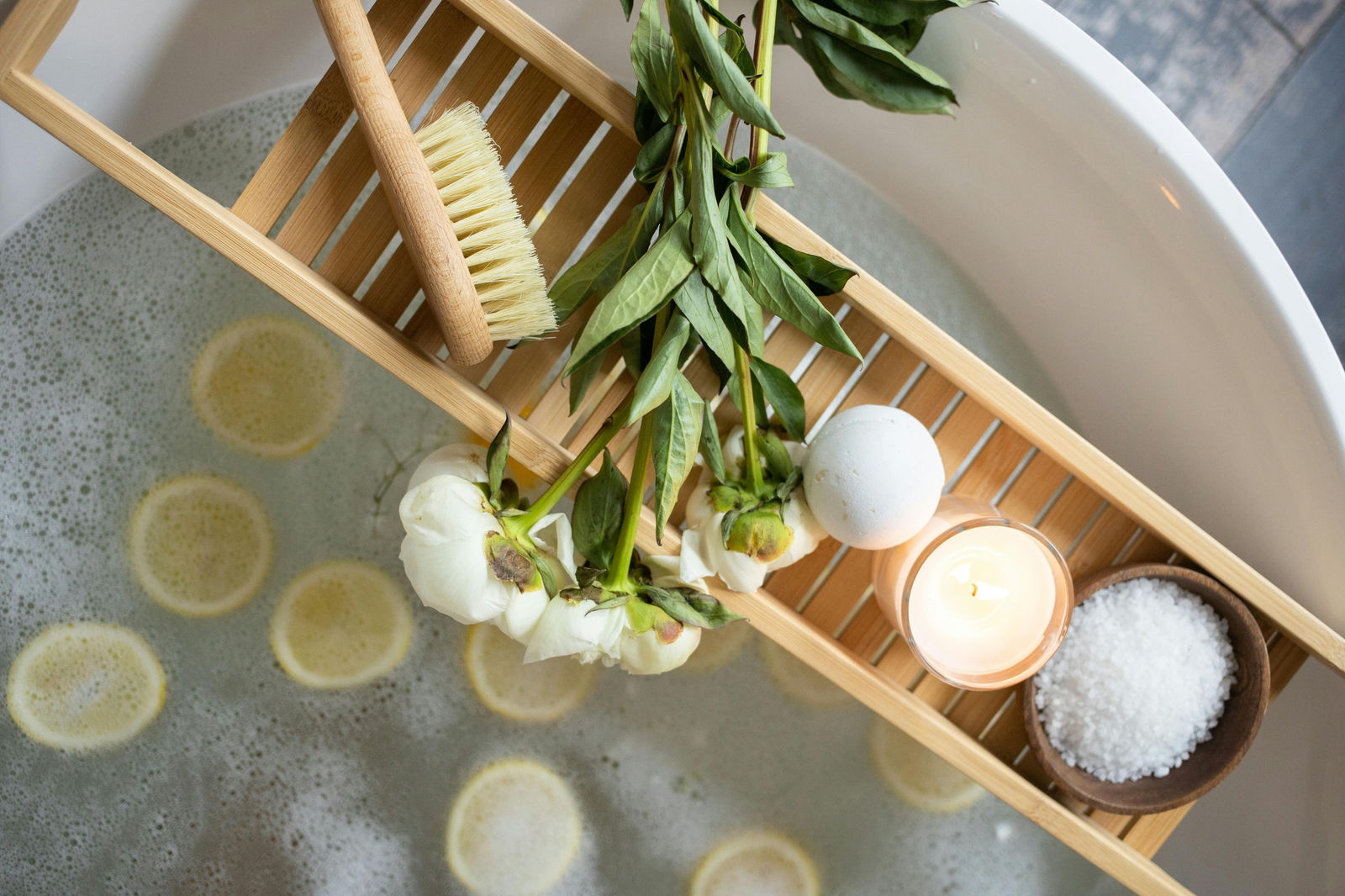 a relaxing bubble bath with Epsom salts, a burning candle, and a bath bomb
