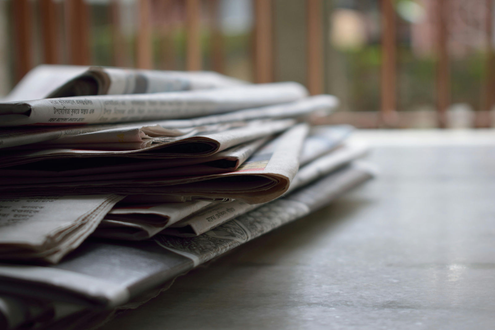 stack of newspapers piled up on outside porch