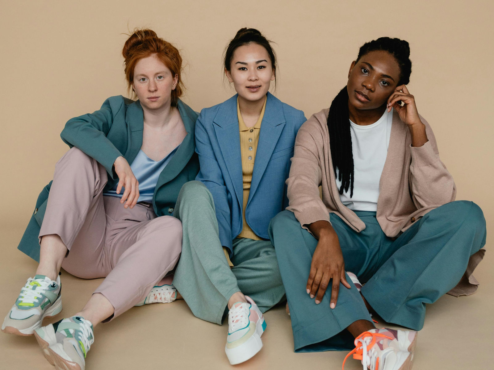 Three different women of different ethnicities sitting next to each other on the floor